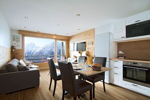 Eine moderne Küche mit Essbereich, Holzelementen und Blick auf schneebedeckte Berge.