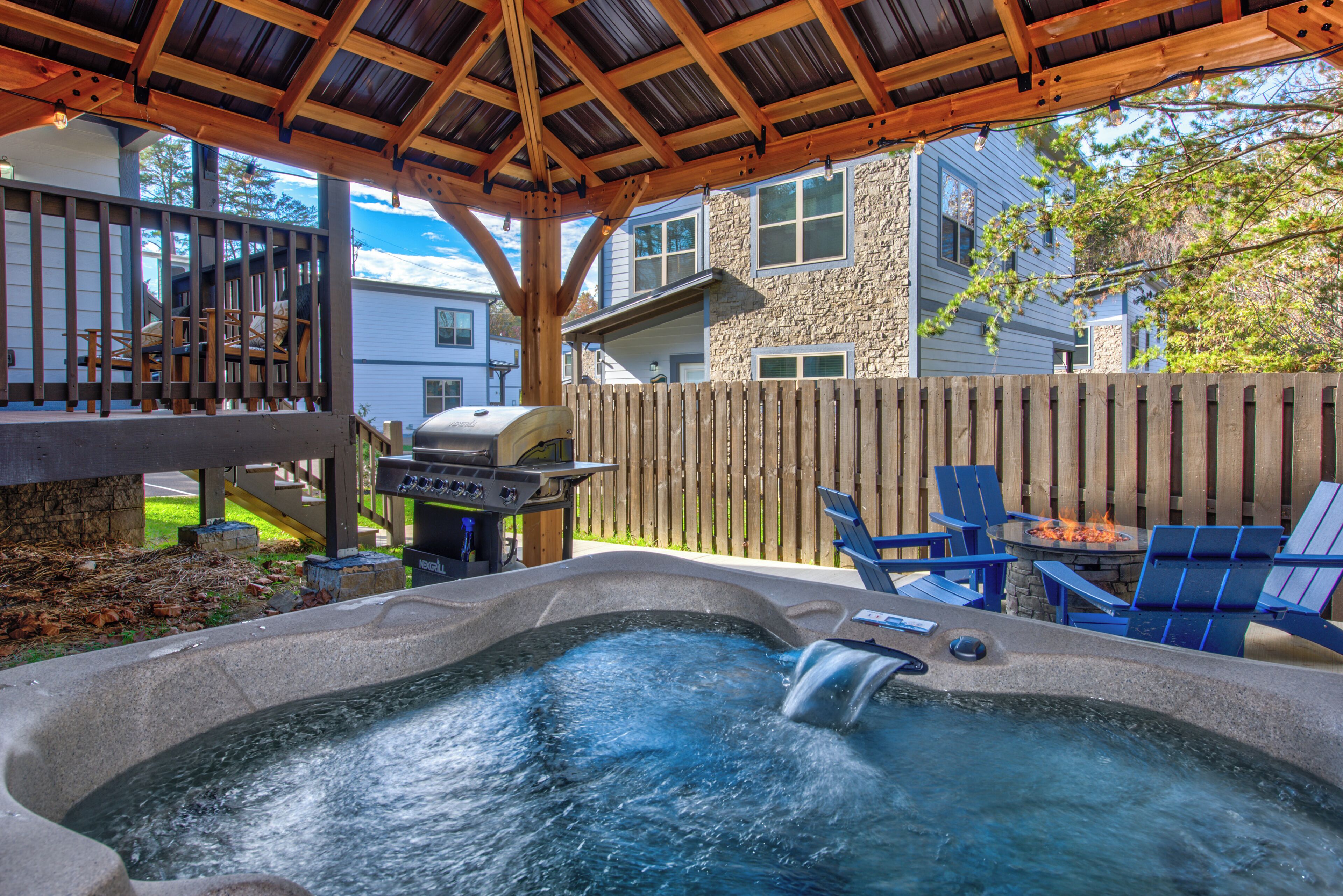 A backyard with a hot tub, barbecue grill, and outdoor seating.