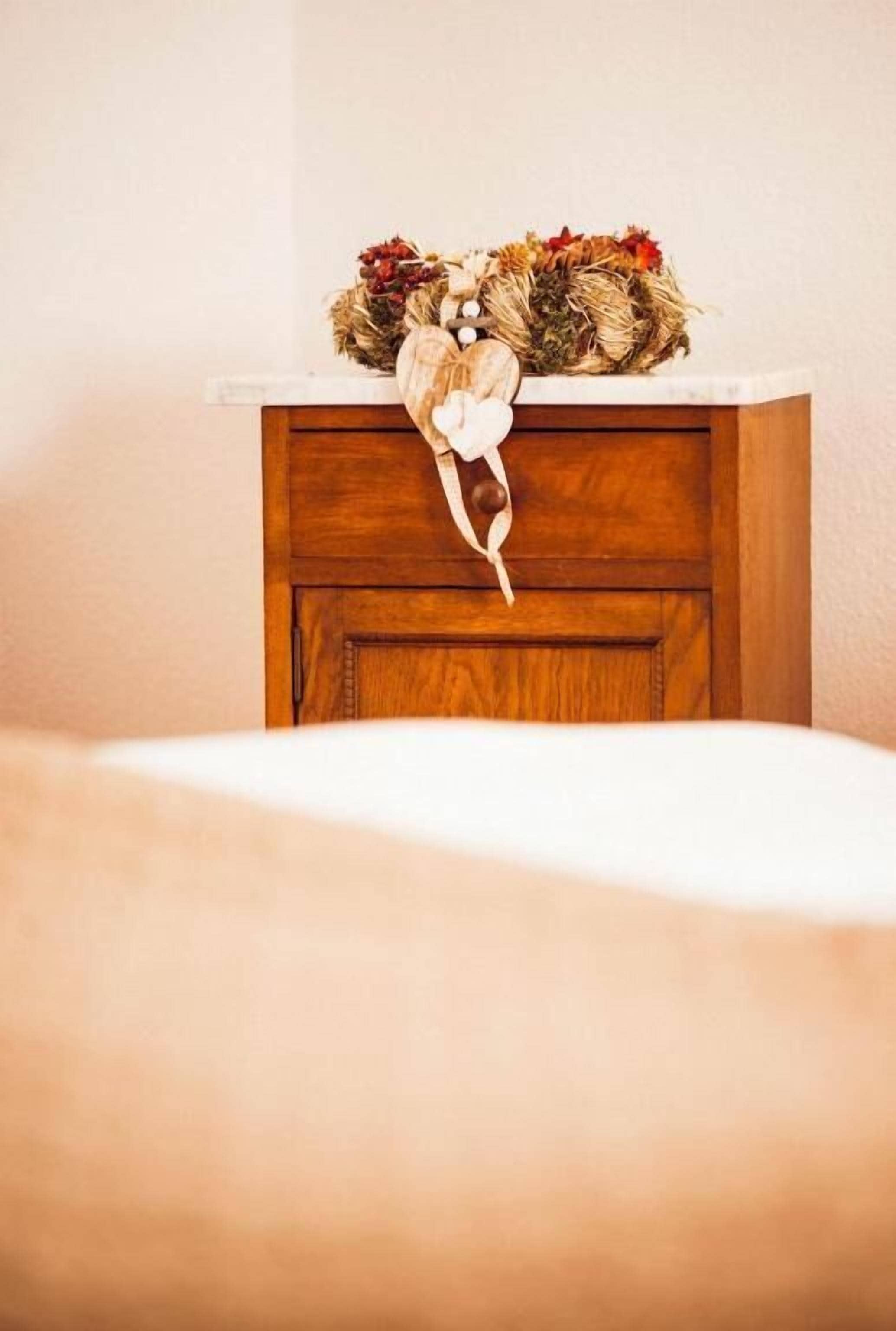 Ein Holzschrank mit dekorativem Kranz auf der Oberseite.