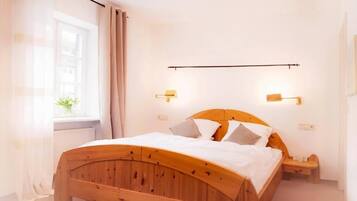 A room with a wooden bed, bedside lamps, and a window with curtains.