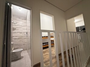 Uma casa de banho moderna com chuveiro, sanita e um banco de madeira.