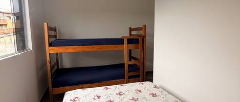 Una habitación con literas, una cama individual con ropa de cama floral, una ventana y un techo blanco.