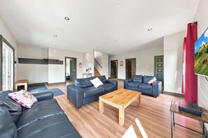 A spacious living area with two sofas, a coffee table, and a TV on a stand. - Spa & Billard | BLANC 21- Stoneham Chalet (Stoneham-et-Tewkesbury)