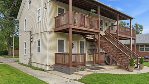 A two-story house with a covered porch and a staircase. - Charming One Bed with Office near Chicago! (Forest Park)