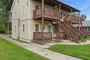 Ein zweistöckiges Haus mit überdachter Veranda und einer Treppe.