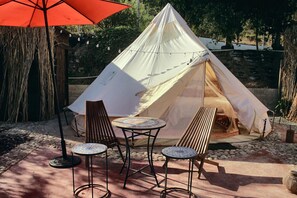 A tent with a table and two chairs in a garden setting.