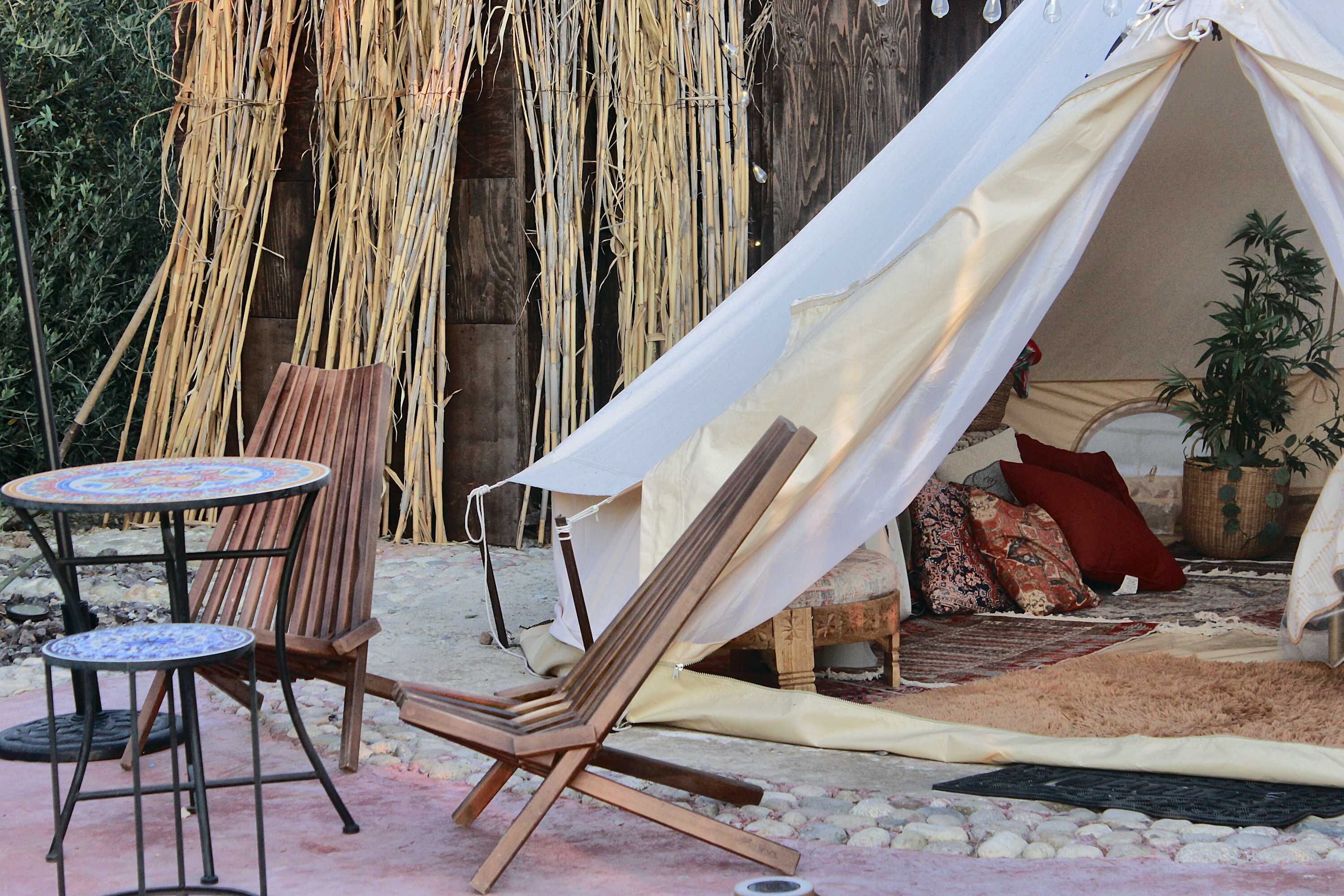 A tent with a white interior, a wooden chair, and a small table with a patterned top.
