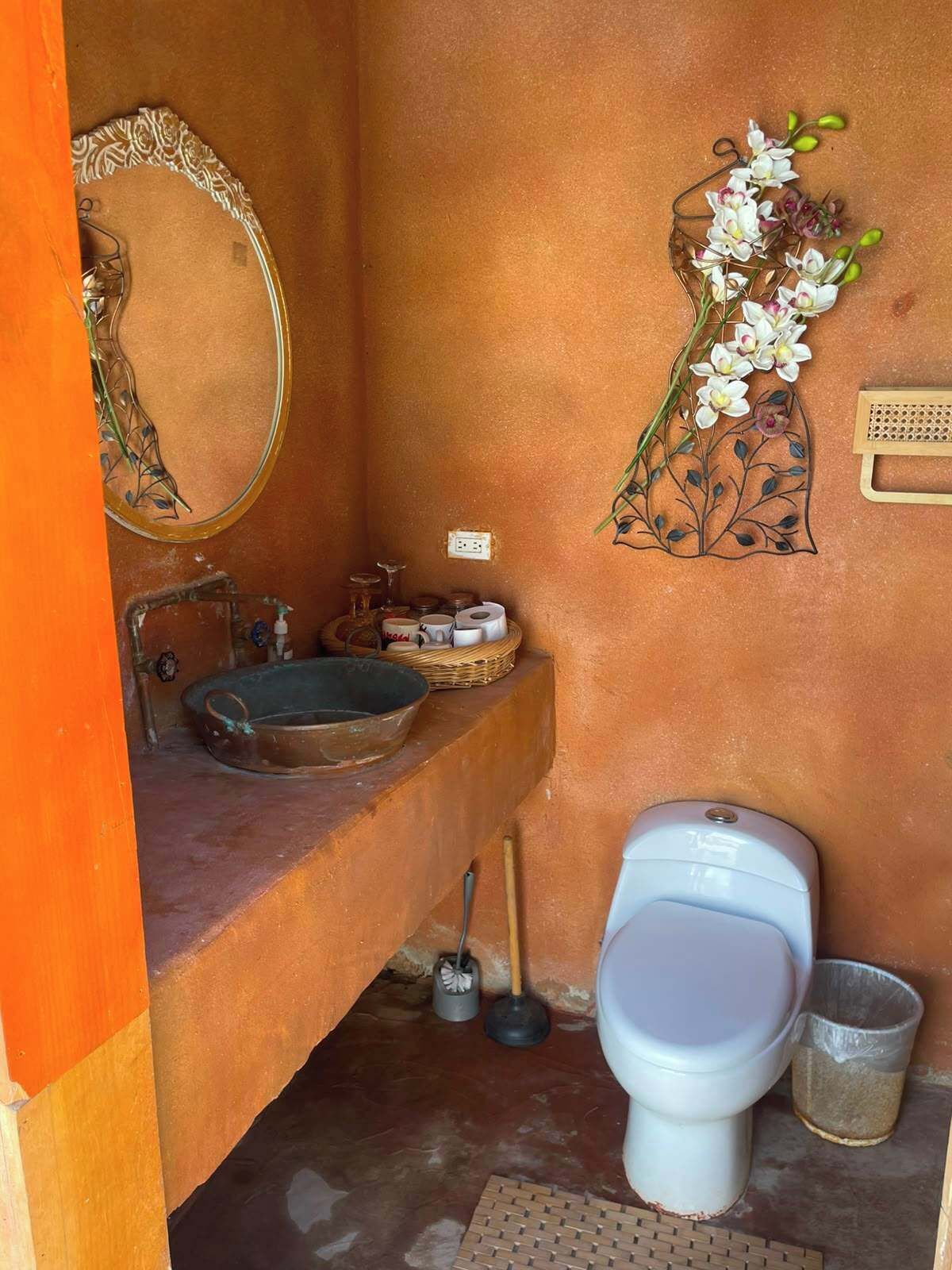 Un baño con lavamanos, espejo, inodoro y decoración en la pared.