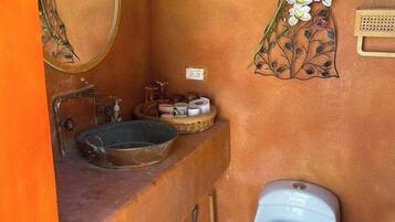 Un baño con lavamanos, espejo, inodoro y decoración en la pared.