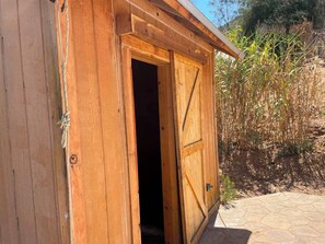 A wooden shed with a door open, revealing an interior.