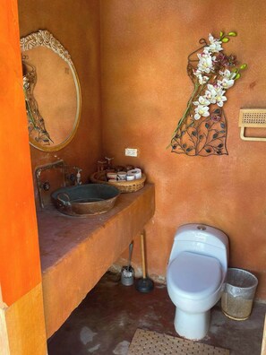 A bathroom with a sink, mirror, toilet, and decorative wall art.