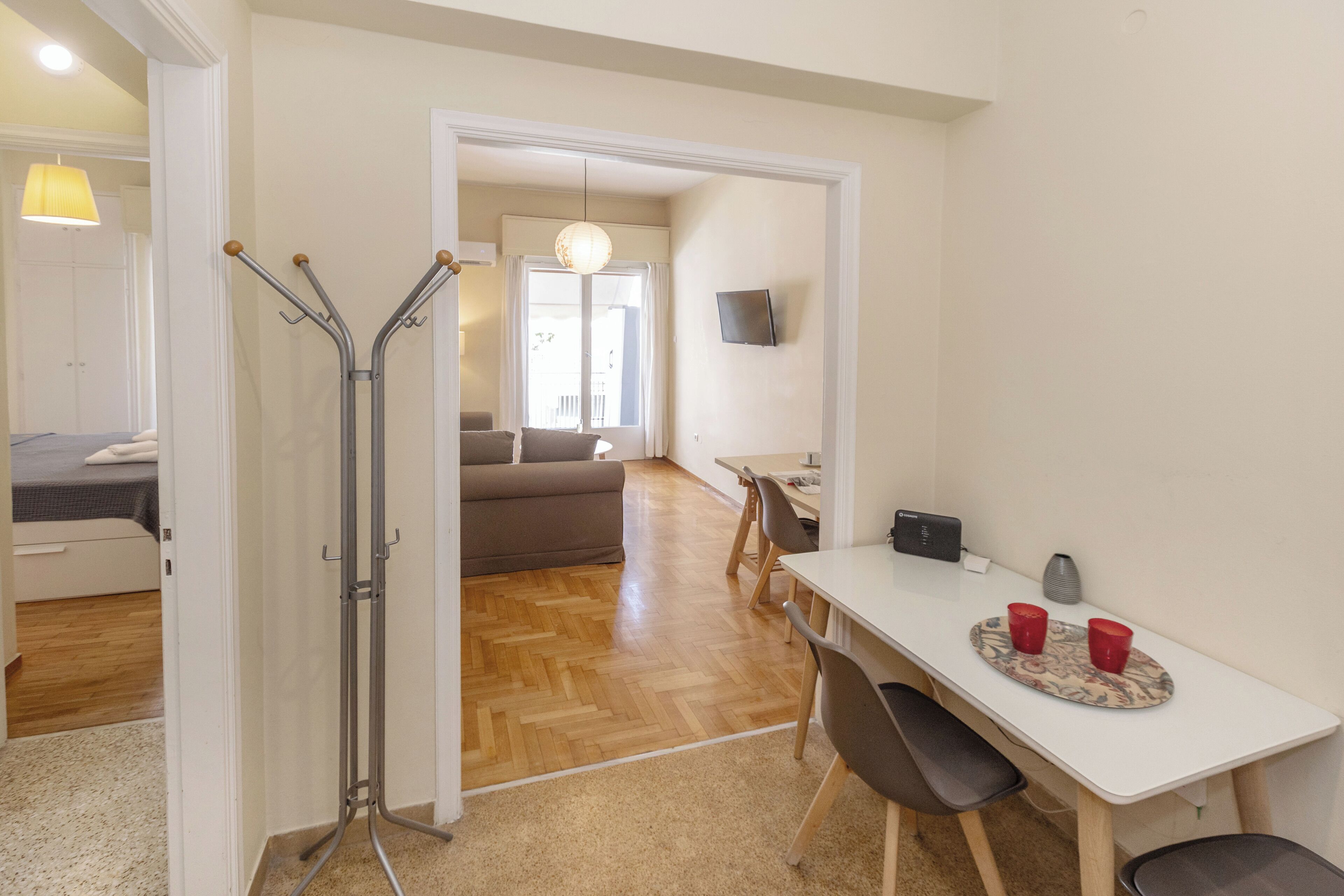 A hotel room with a bed, a desk, a chair, a dining table, and a television.