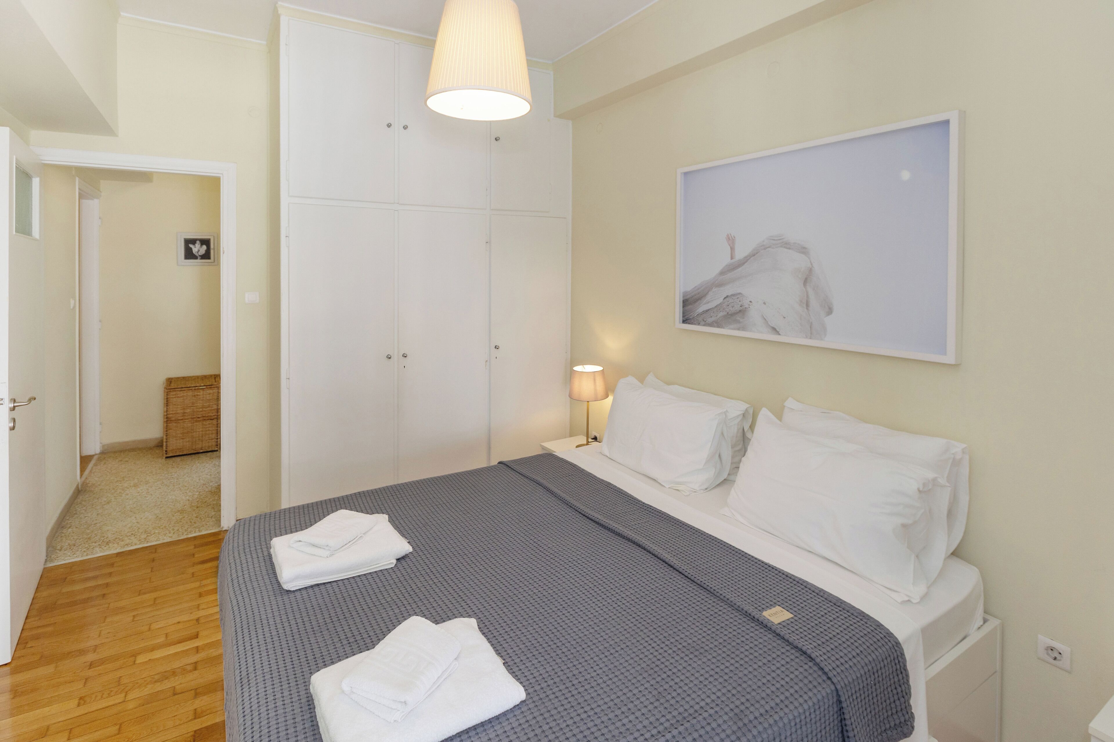 Een slaapkamer met een bed, een bedlamp, een kledingkast en een schilderij aan de muur.