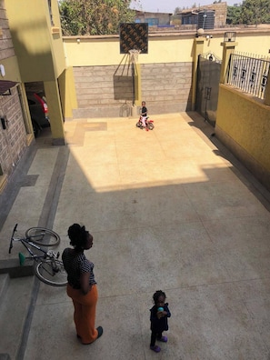 A courtyard with a basketball hoop, a bicycle, and a gated entrance. - Tranquil 1-bedroom apartment in wonderful Nairobi neighborhood (Nairobi)