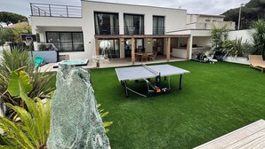 Ein modernes Haus mit Tennisplatz, Schwimmbad und einer Terrasse.