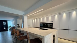 Eine moderne Küche mit Marmorarbeitsplatte, integrierten Geräten und einer Sitzecke mit Korbstühlen.