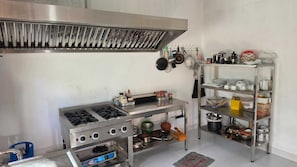 A kitchen with a gas stove, stainless steel shelves, and various kitchen utensils. - A boutique lagoon villa featuring two AC rooms and a restaurant. (Negombo)