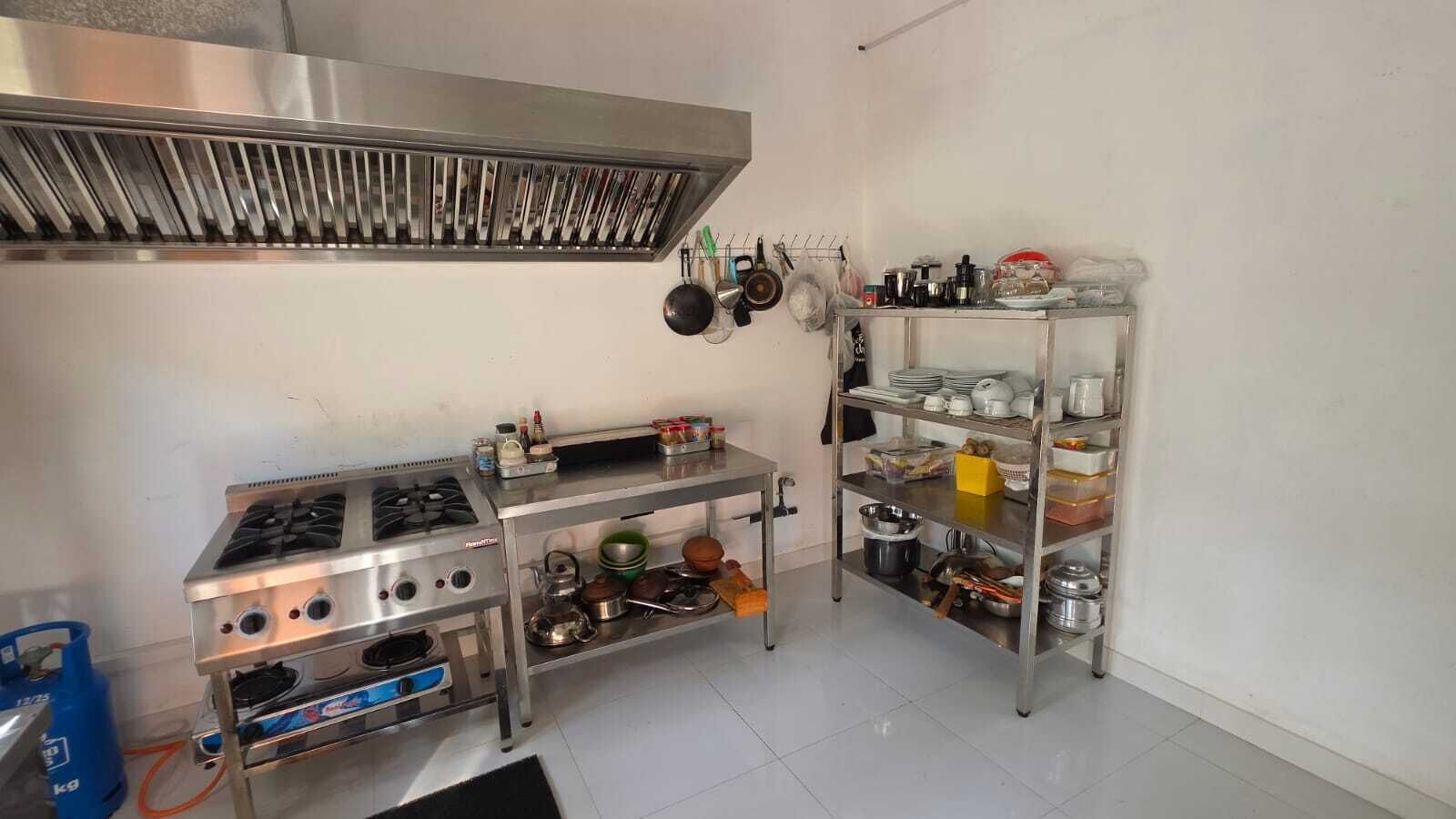 A kitchen with stainless steel appliances, including a stove and a range hood, and shelves with kitchenware.