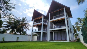 A multi-story building with balconies, surrounded by a well-maintained lawn and palm trees.