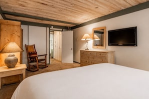 A bedroom with a bed, a dresser, a chair, a lamp, a television, and a door leading to another room. - Short Walk to Canyon 683 (Mammoth Lakes)