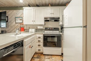 A compact kitchen with white cabinets, a built-in oven, a dishwasher, and a stainless steel sink. - Short Walk to Canyon 683 (Mammoth Lakes)