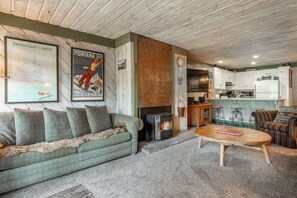 A cozy living room with a green sofa, a wooden coffee table, and a fireplace. - Short Walk to Canyon 683 (Mammoth Lakes)