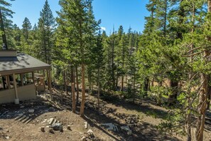 A cabin with a covered porch, surrounded by dense forest. - Short Walk to Canyon 683 (Mammoth Lakes)