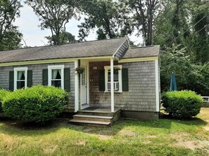 Une maison de plain-pied avec un porche à l’avant, un petit jardin devant et une boîte aux lettres.