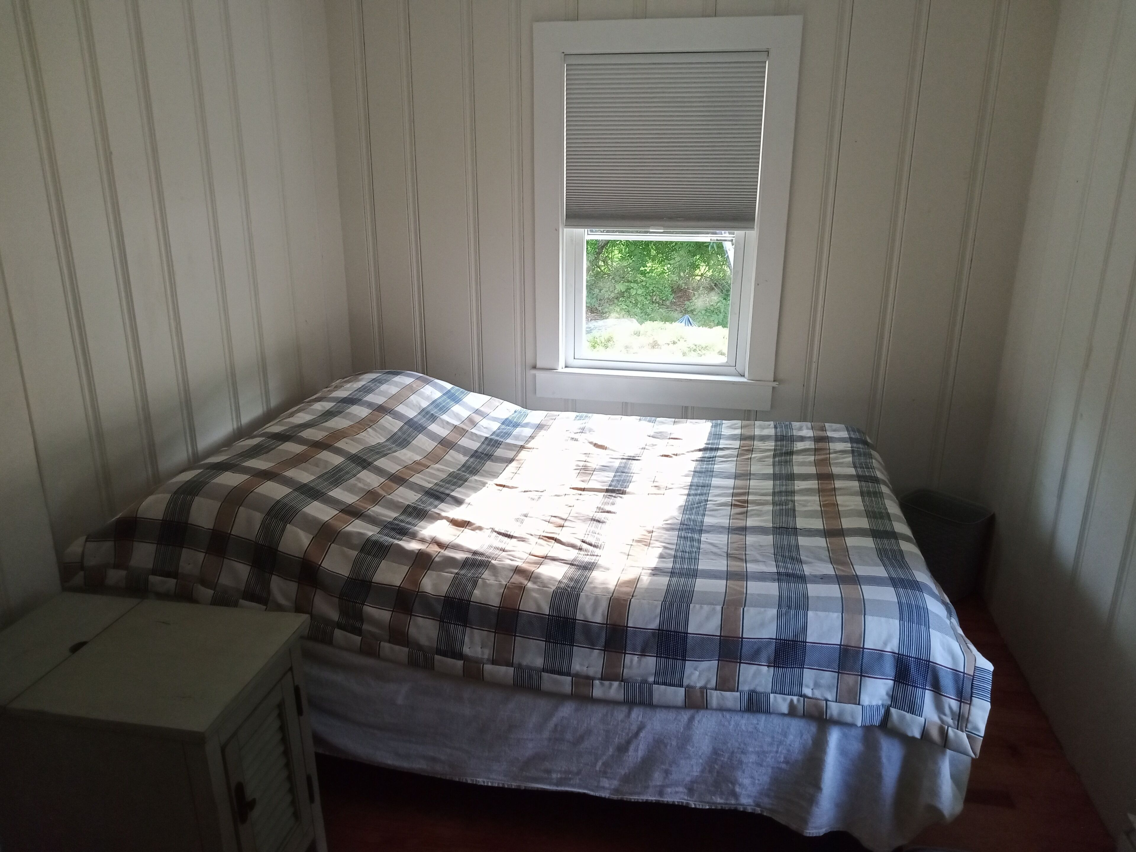 Un dormitorio pequeño con una cama individual, una ventana con persianas y un aparador blanco.