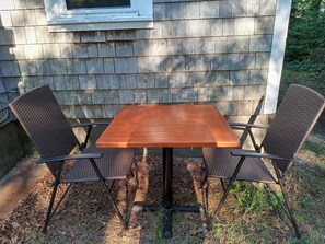 A wooden table with four chairs in an outdoor setting. - Cozy 2BR cottage, walk to beaches, restaurants, mini golf. (Yarmouth)
