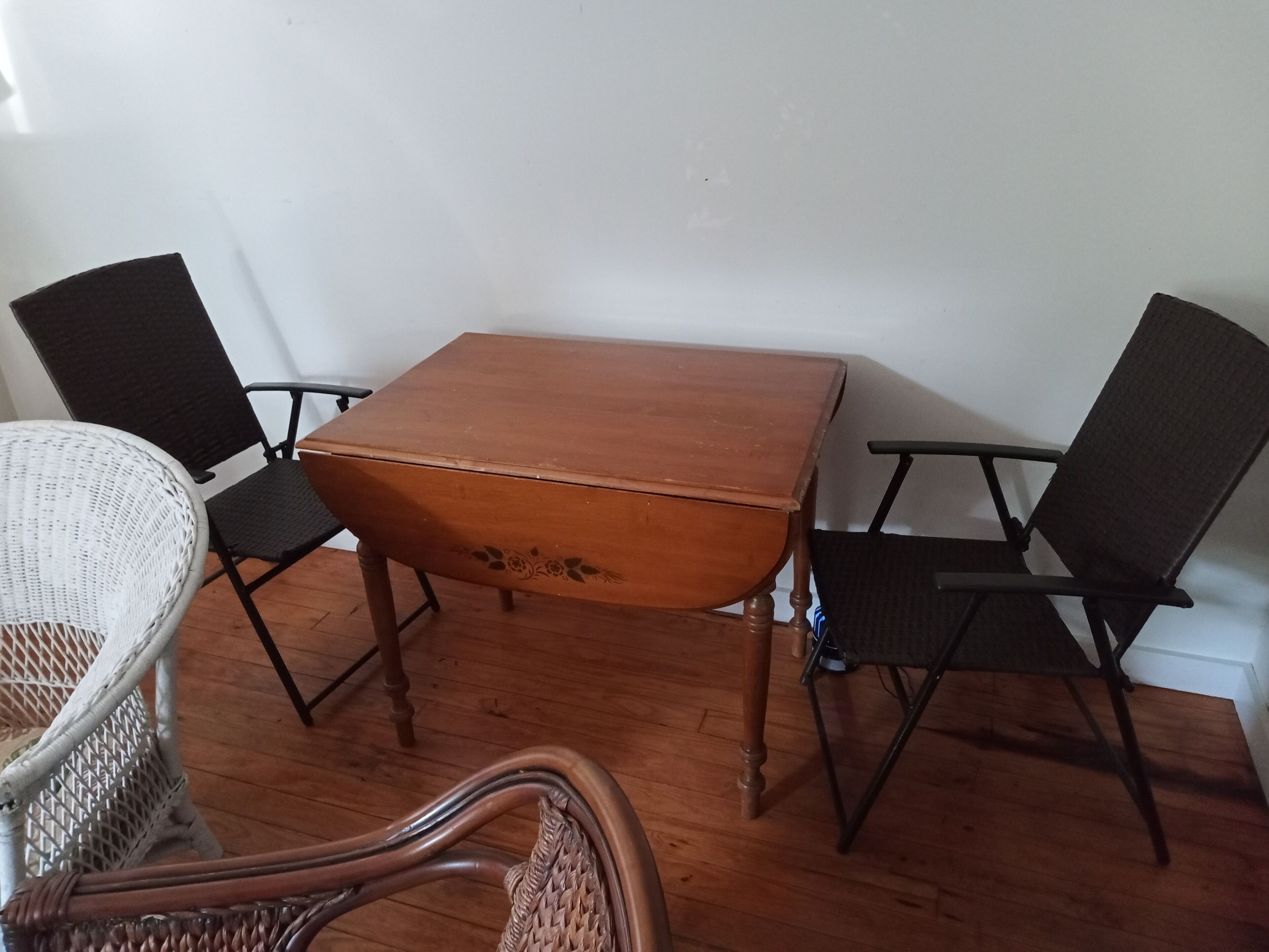 A wooden dining table with four chairs, two of which are wicker and two are black.