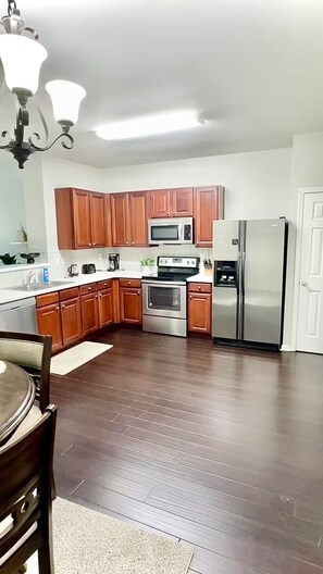Una cocina moderna con gabinetes de madera, electrodomésticos de acero inoxidable y piso de madera oscura.