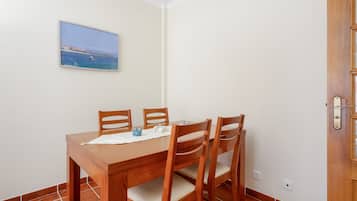A dining area with a wooden table and four chairs, a small decorative item, and a framed picture on the wall.