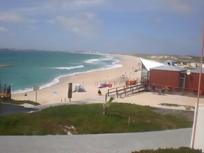 A beach view with a building, a clear sky, and a calm sea.