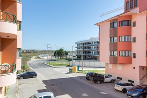 A residential area with multi-story buildings, a curved road, parked cars, and a clear sky.