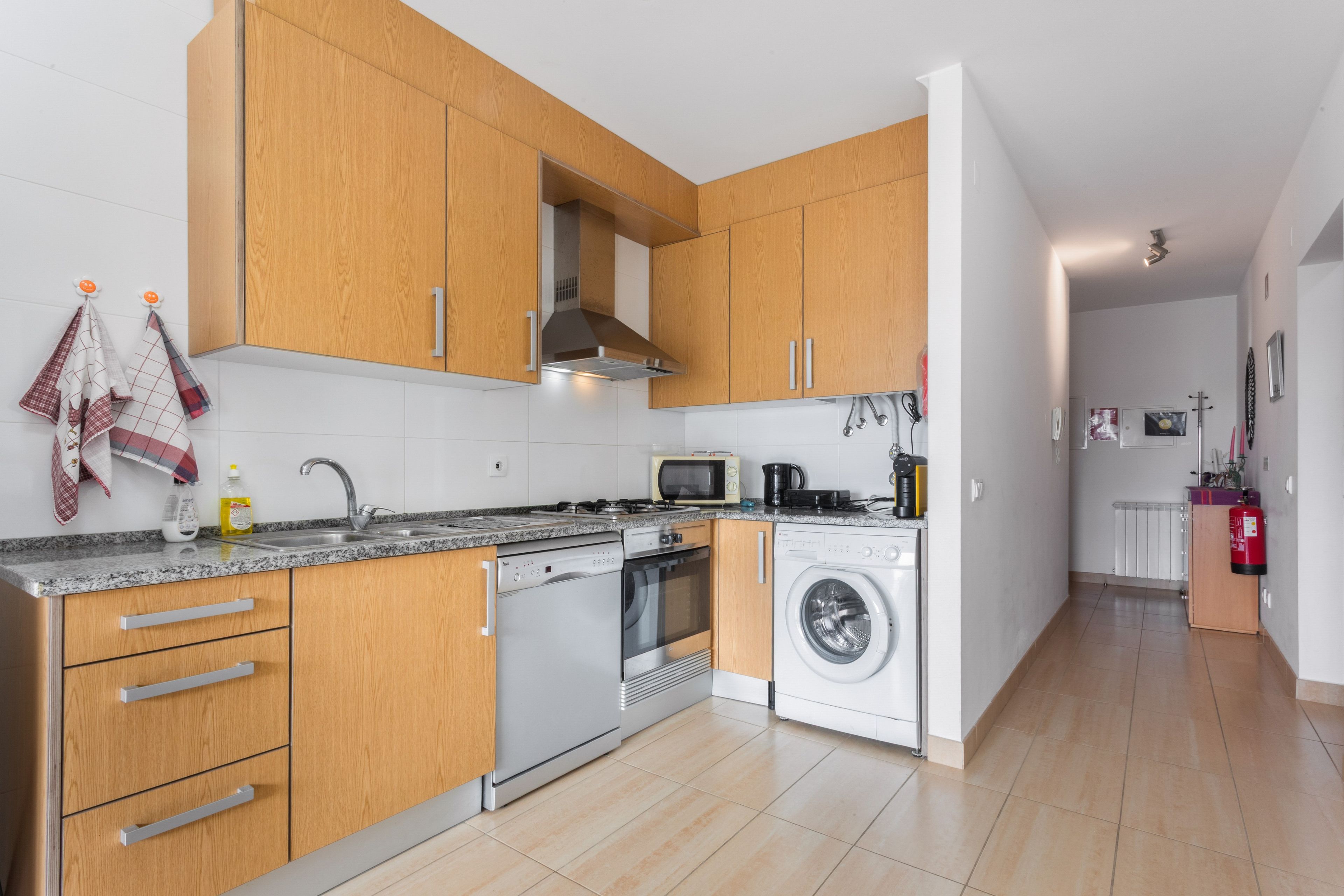 Una cocina moderna con armarios de madera, electrodomésticos de acero inoxidable y salpicadero de azulejos.