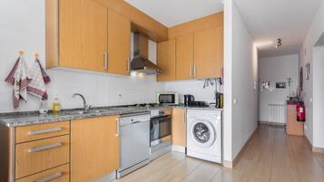 Una cocina moderna con armarios de madera, electrodomésticos de acero inoxidable y salpicadero de azulejos.