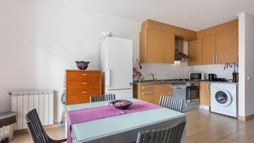 A modern kitchen with wooden cabinets, a built-in oven, microwave, and washing machine.