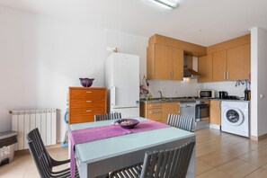 Una cocina moderna con armarios de madera, horno empotrado, microondas y lavadora.