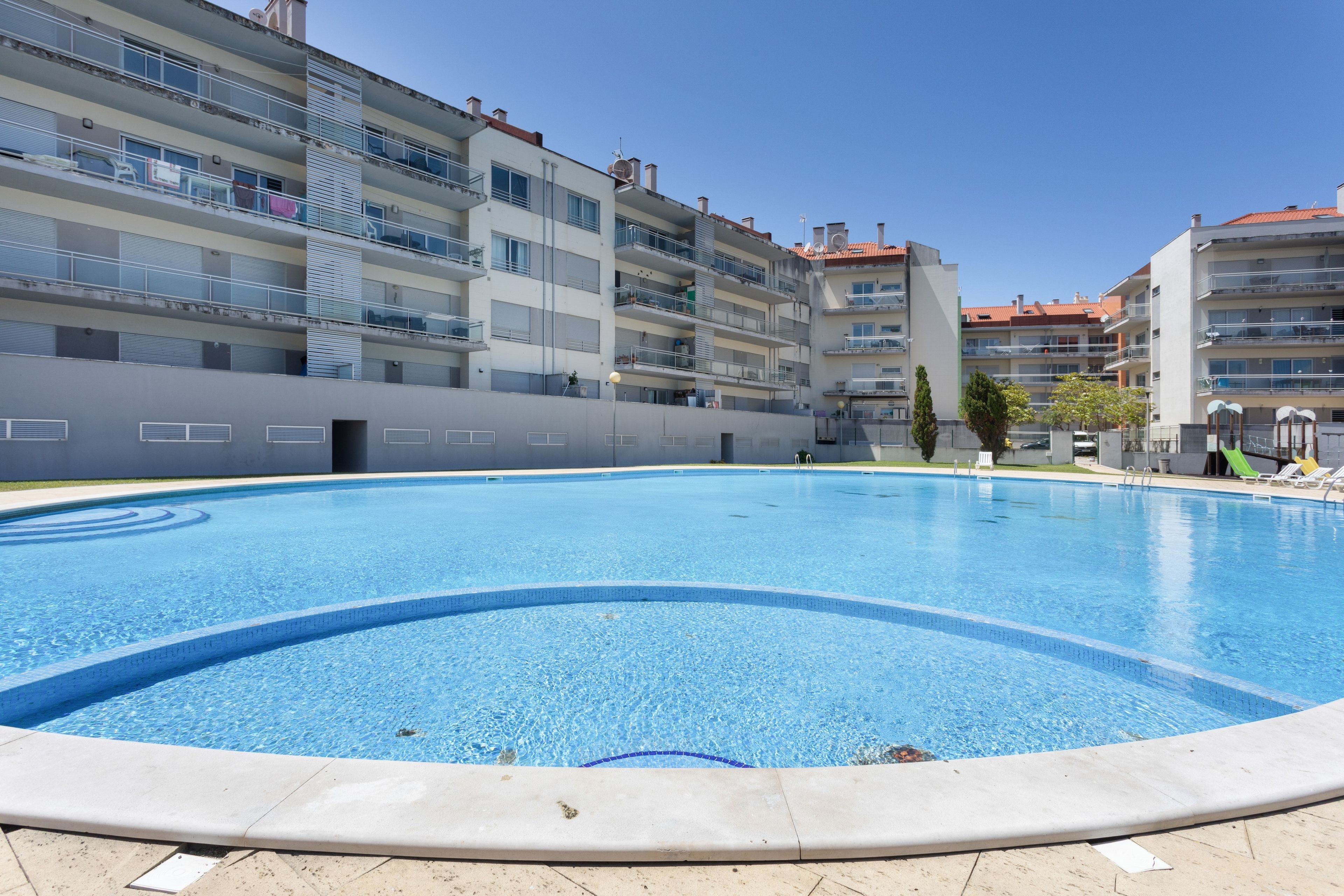 Una piscina rodeada de edificios residenciales de varios pisos con balcones.