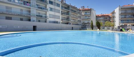 A swimming pool surrounded by multi-story residential buildings with balconies.