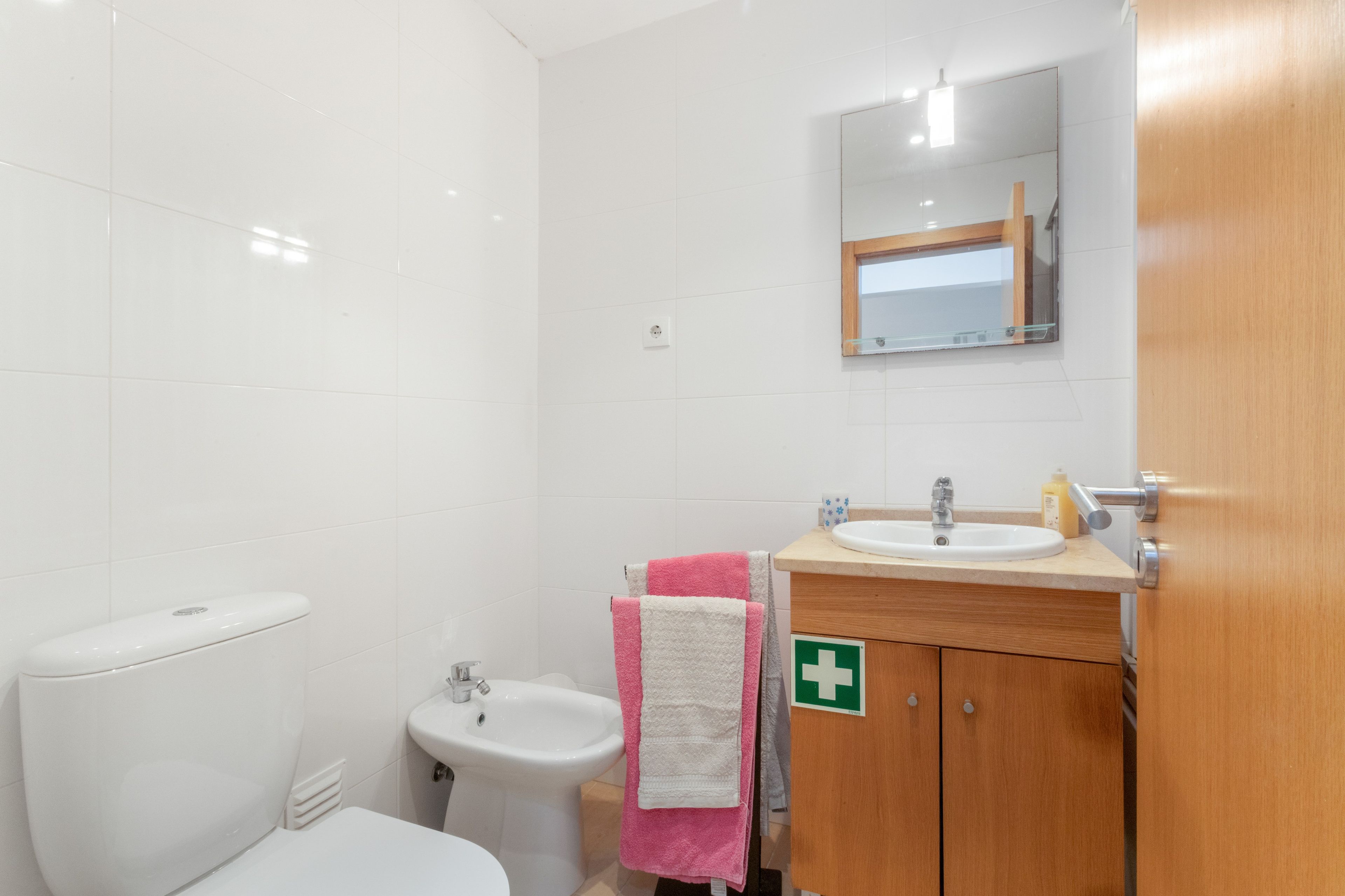 Un baño con inodoro, bidé, lavabo y un espejo sobre el lavabo.