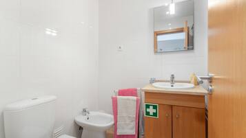 Un baño con inodoro, bidé, lavabo y un espejo sobre el lavabo.