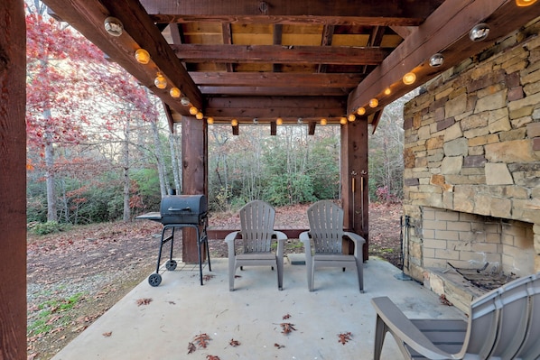 An outdoor patio with a stone wall, wooden pergola, and string lights.