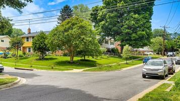 A residential street with houses, a car, and trees.