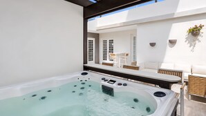 A hot tub with a control panel, a white outdoor seating area with a table and chairs, and a hanging plant. - Stunning Villa - 1 Block from the Beach (San Juan)