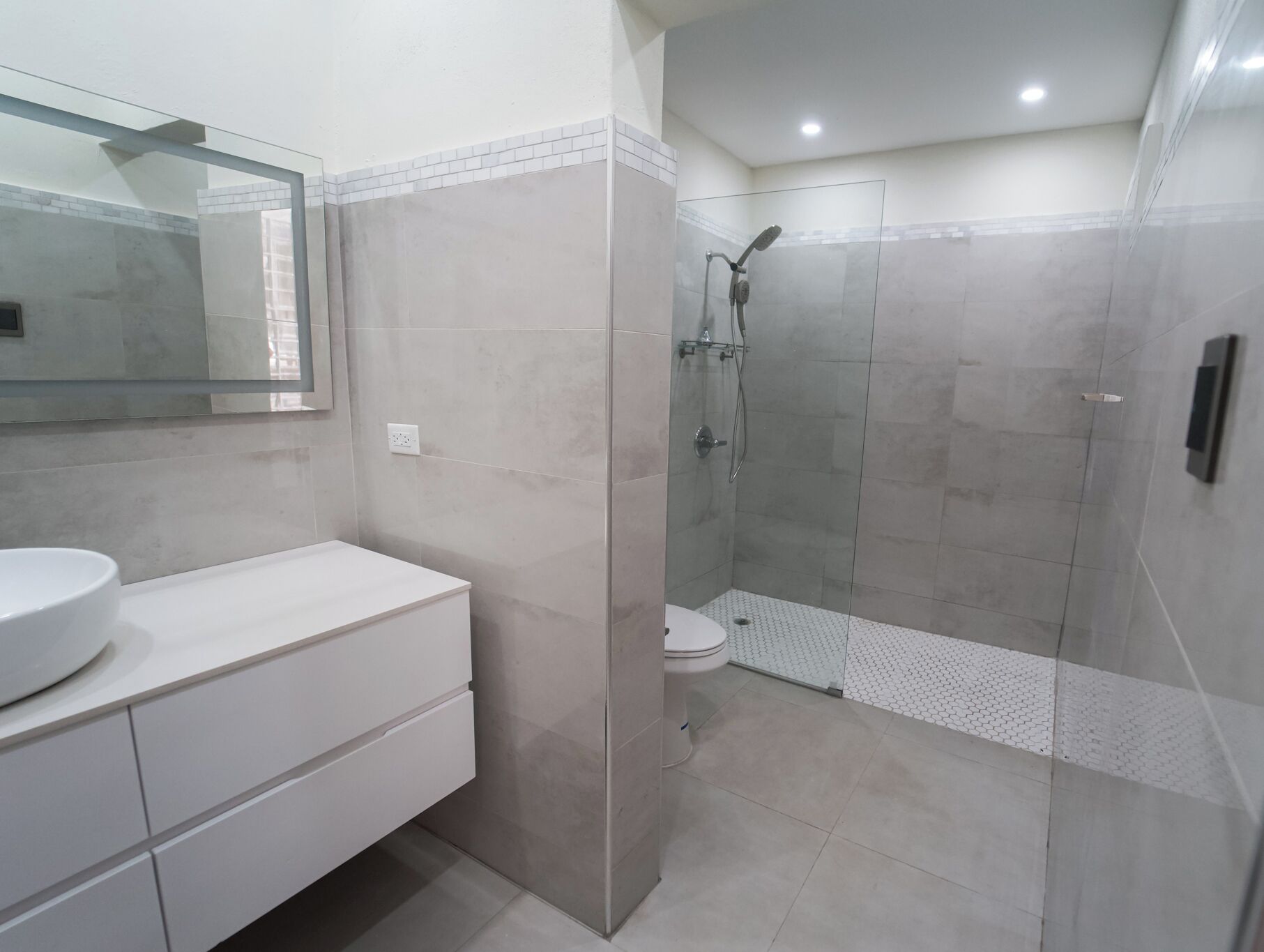 A modern bathroom with a glass-enclosed shower, a white sink, and a large mirror.