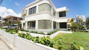A two-story building with a flat roof, large windows, and a well-maintained lawn. - Stunning Villa - 1 Block from the Beach (San Juan)