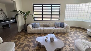 A living room with a sofa, coffee table, and a pool table. - Stunning Villa - 1 Block from the Beach (San Juan)