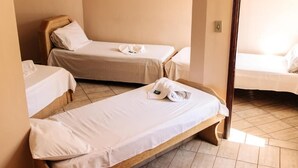 A hotel room with two single beds, a wooden headboard, and a small table.